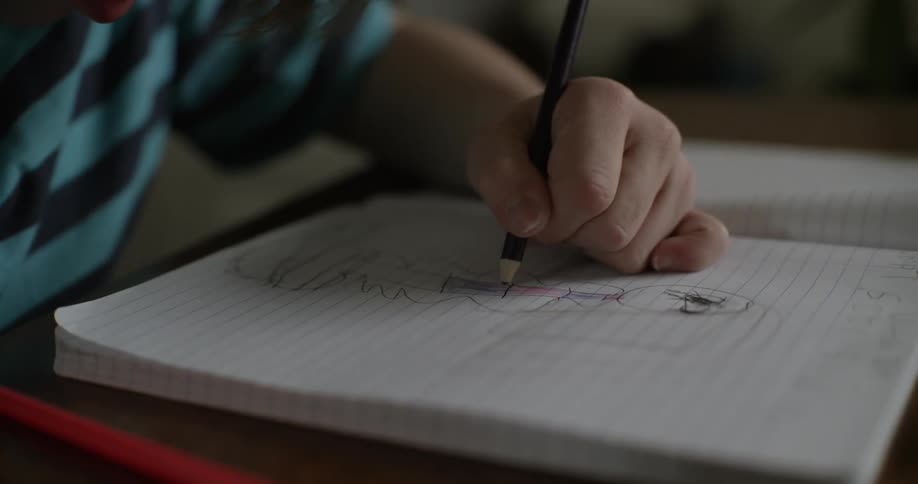 Young person draws in notebook with pencil