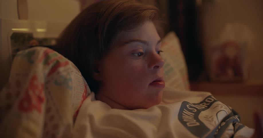 A woman is looking at something while laying in bed