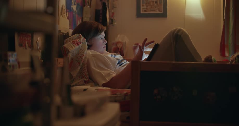 A woman is laying in bed playing on atablet