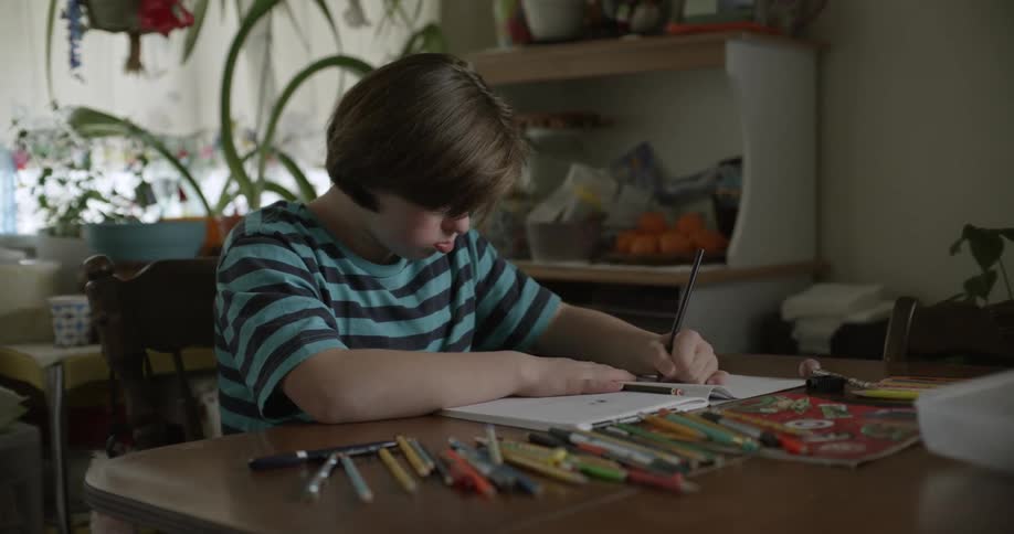 Teenager girl colors with pencils in notebook while sitting at table