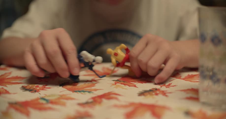 A girl plays with hockey player figurines while sitting at her dining room table