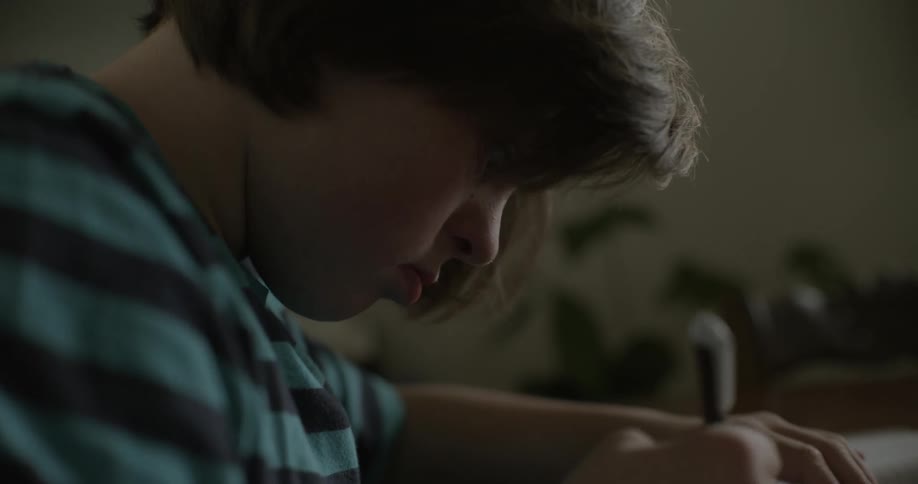 A child is sitting at a desk drawing in a notebook