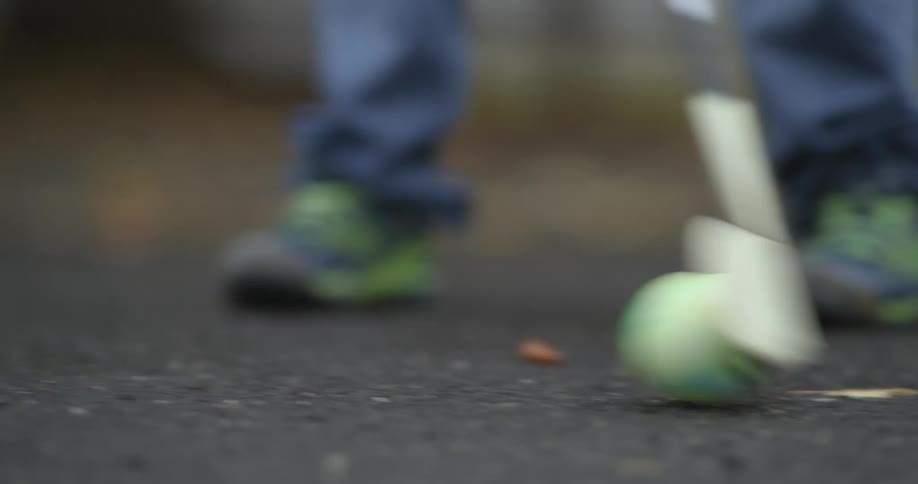 A child hits a ball back and forth with a stick and then shoots it