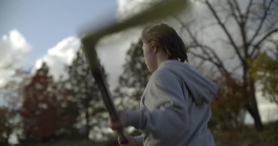 A child playing street hockey in a neighborhood cheers