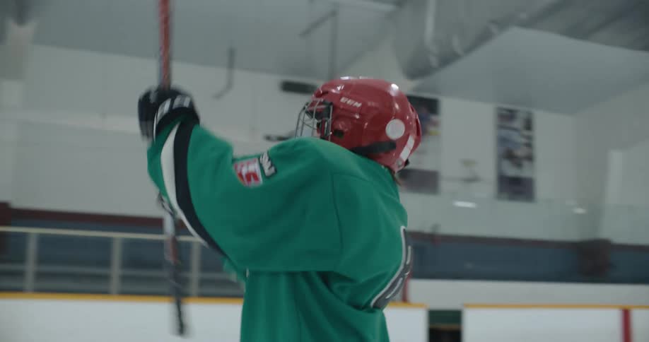 Ice hockey player takes swing at hockey puck then cheers