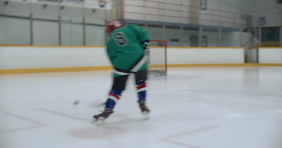 A hockey player is on the ice at a rink practicing shooting pucks