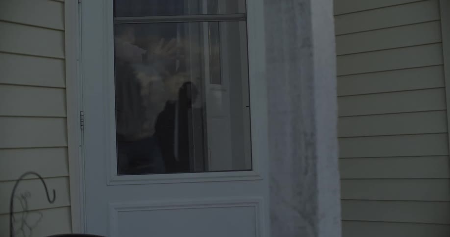 Teenage girl exits house door and runs down sidewalk with hockey stick