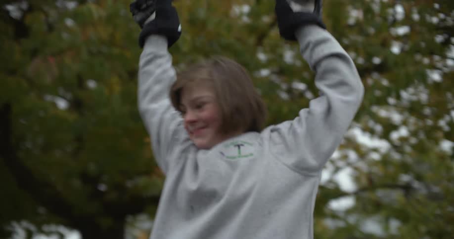 A person uses a hockey stick in a neighborhood road and celebrates with raising their arms