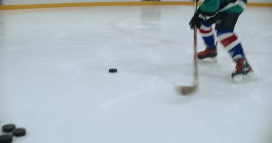 Hockey player practices making goals with a pile of hockey pucks