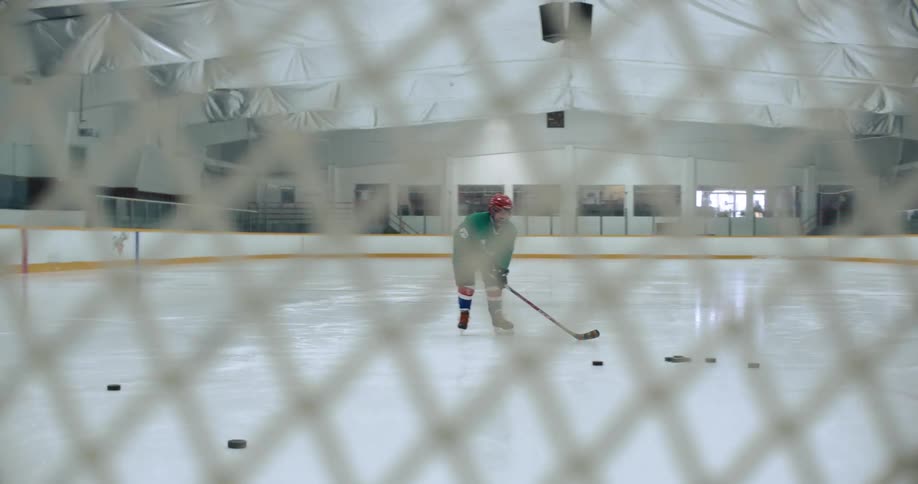 A girl practices hitting hockey pucks in a rink