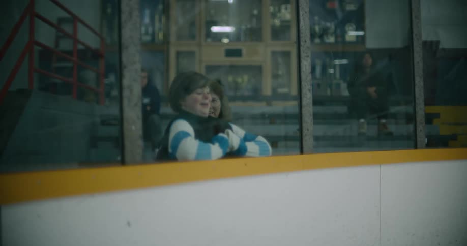Hockey players skate across the rink and crash into the side wall in front of spectators