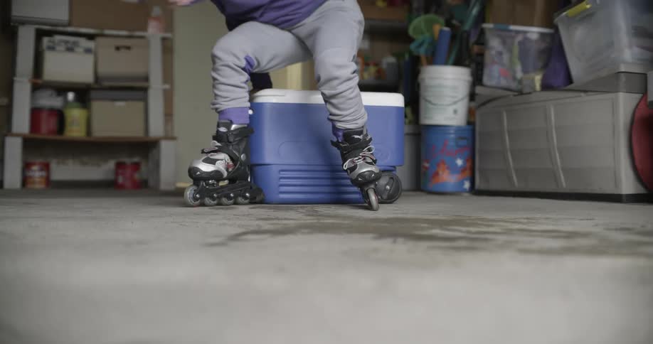 A girl stands up and skates out of her garage