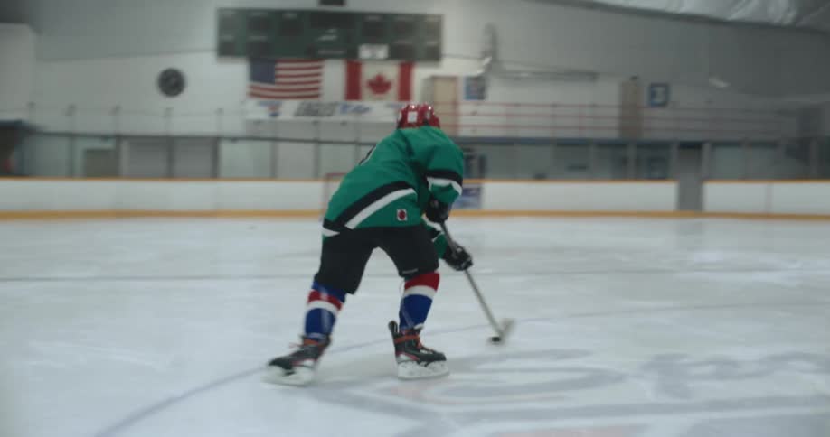 A hockey player dribbles a hockey puck across the ice