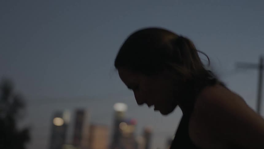 A woman jogs in place in the street at night