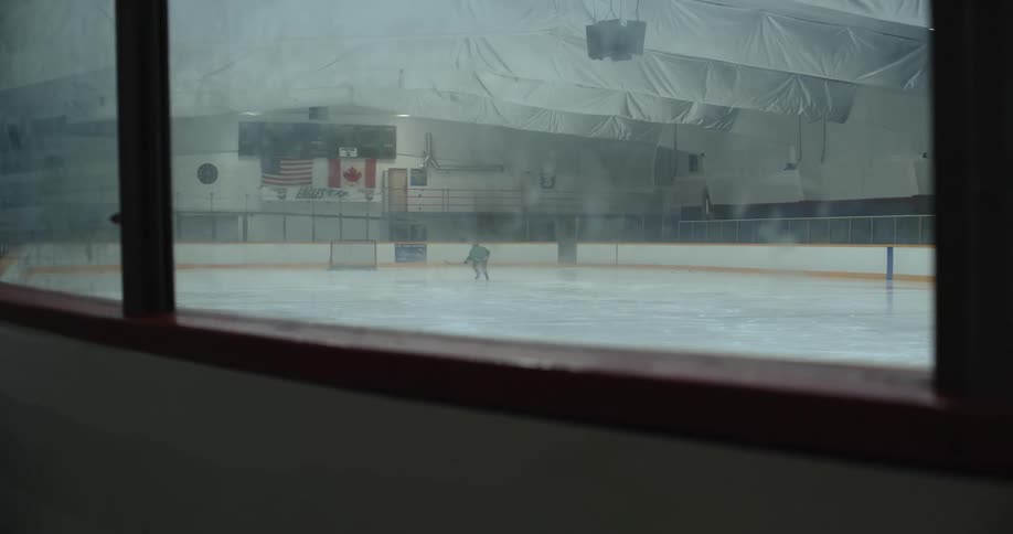 Young girl practices hockey moves on an indoors skate rink
