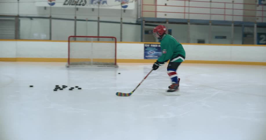 Young girl practices shooting hockey pucks into the goal