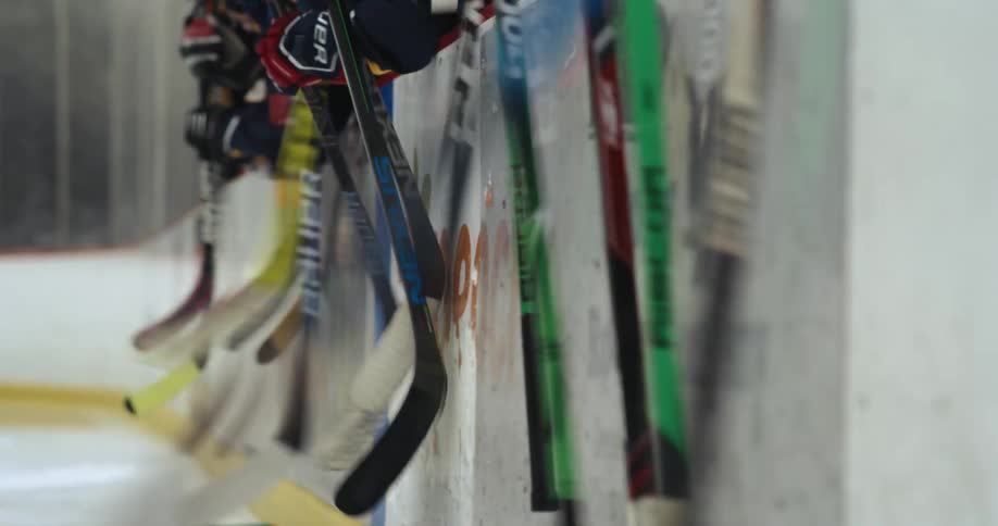 Team of young hockey players beating the wall on the rink with their sticks
