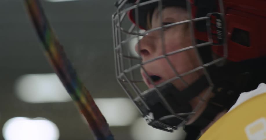 A young girl dressed in hockey gear is resting and looking around