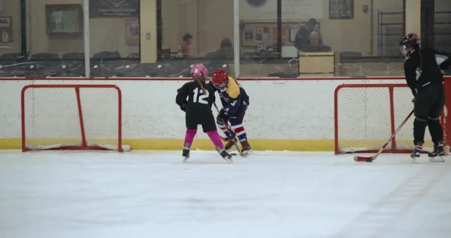Young hockey players are practicing taking shots and blocking on the ice in an ice rink