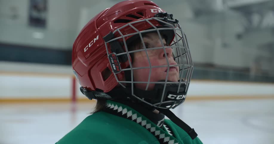 A hockey player looks up as she stands in the rink