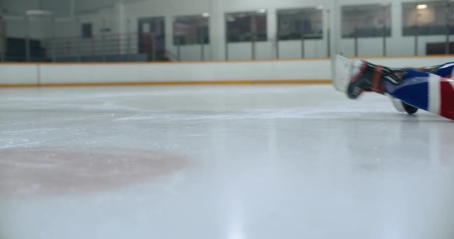 Athlete in hockey uniform falls and slides across ice rink