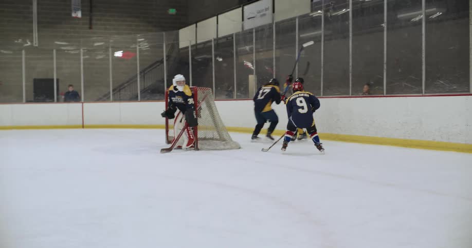 Teams of hockey players are playing a game in an indoor arena