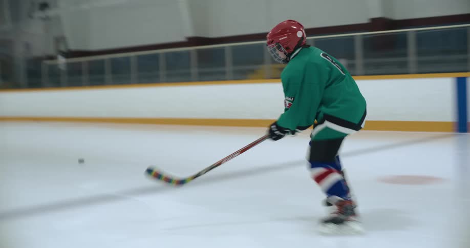 A hockey player skates across the ice after a puck