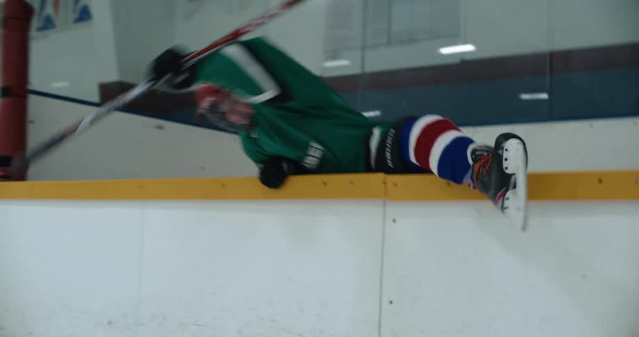 A hockey player climbs over the wall
