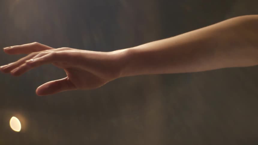 A dancer holds her arm and hand out gracefully in a pose