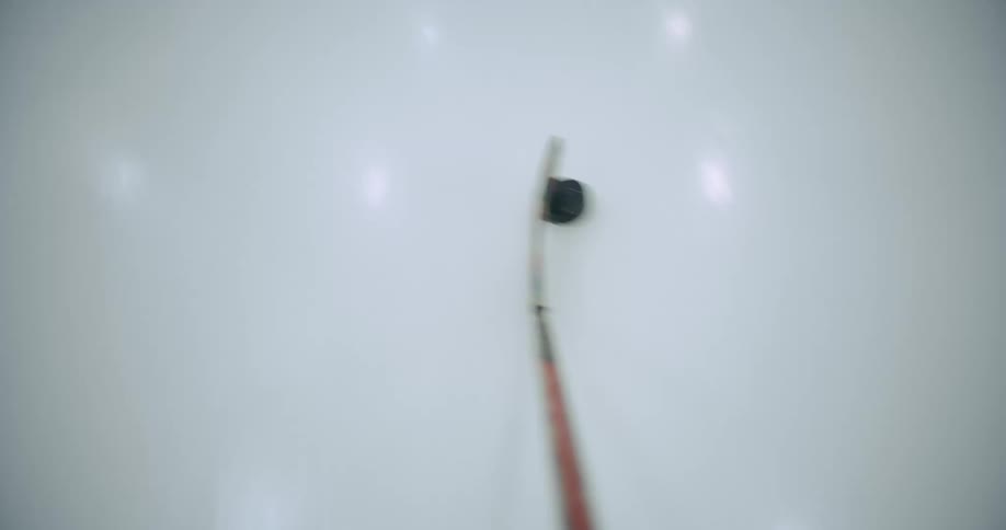 Hockey player skates across rink directing puck toward goal