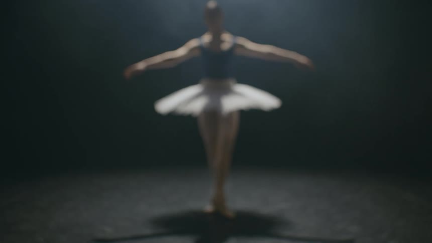 A woman is performing ballet under the spotlight