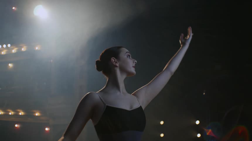 A woman is performing ballet on stage under the lights