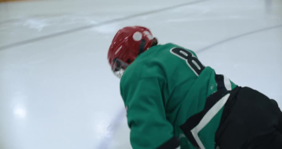Hockey player skates across ice rink falling and sliding across surface