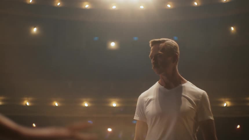 A ballet teacher watches his student practice on stage