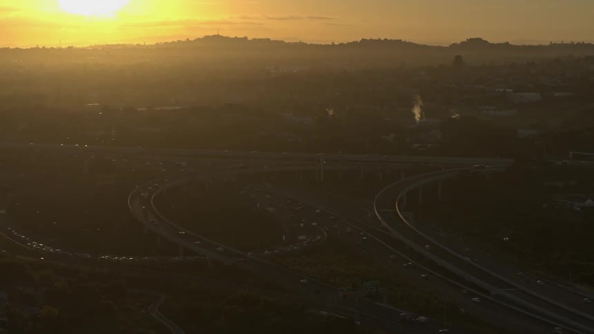 Traffic travels along a large highway interchange at sunset