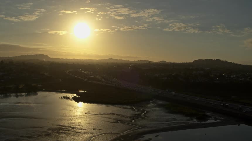 Sun setting behind freeway/cityscape in Auckland, New Zealand