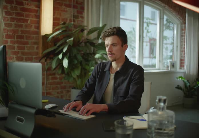 Young man sitting at a desk working on a computer at home