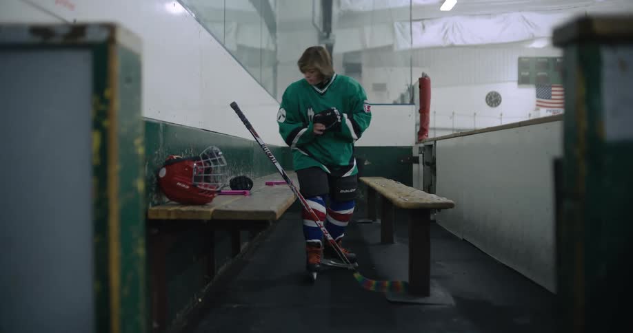 A young female hockey player gets her equipment together before heading for the ice