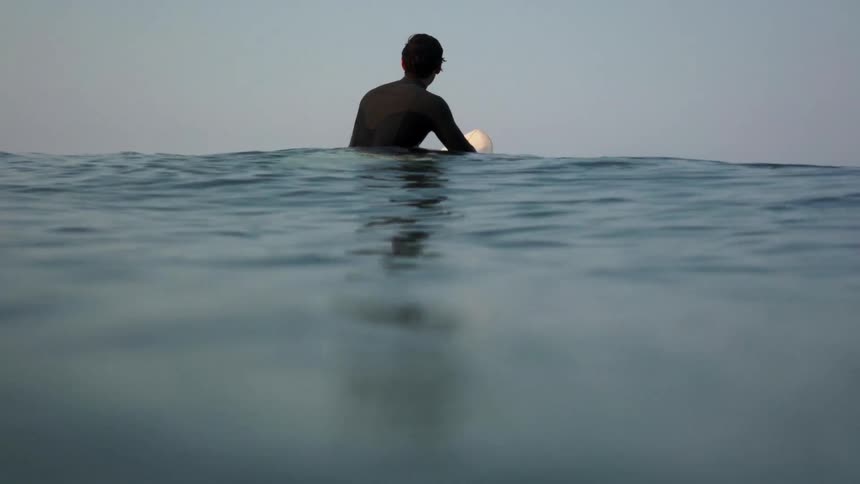A man is floating in the water on a surfboard