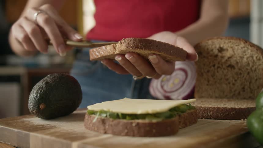 A woman spreads on a condiment on her sandwich