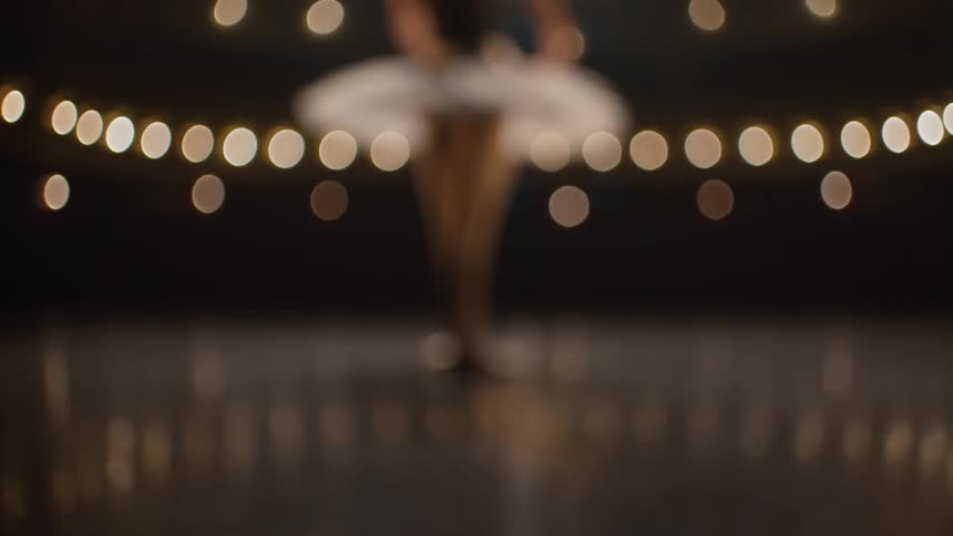 Ballerina walks onto stage in theater and takes dance pose