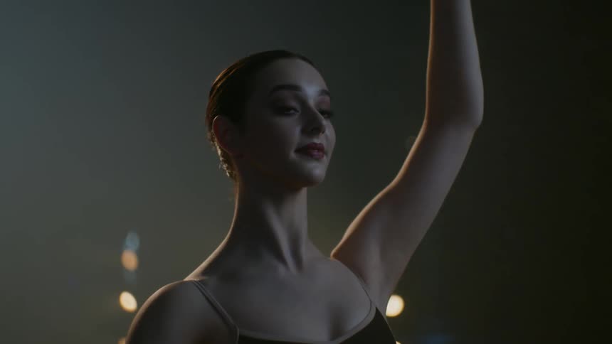 A ballerina slowly dances in a theater