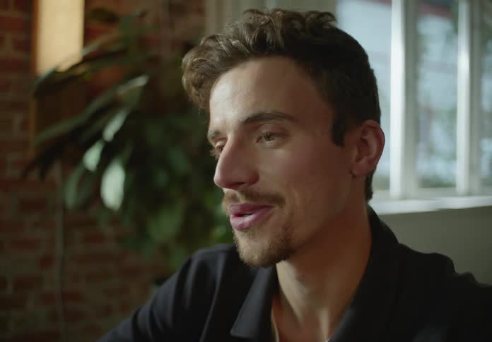 A man is looking forward and smiling as he talks to someone