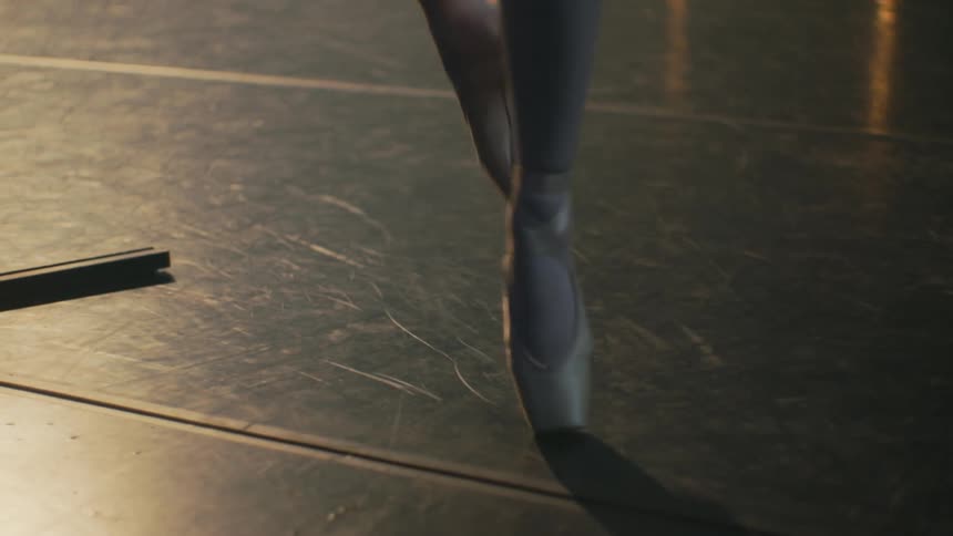 A ballerina practices barre on a stage