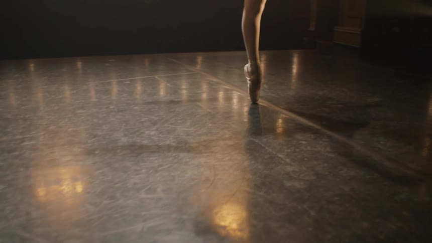 A ballerina dances on stage with theater lights glowing