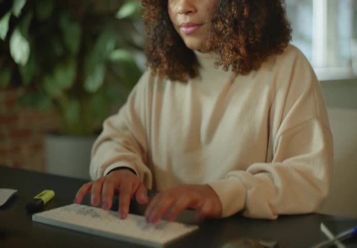 A woman types on a wireless keyboard while sitting at a desk