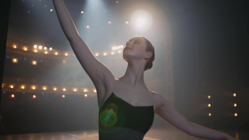 Ballerina moves through dance poses on theater stage
