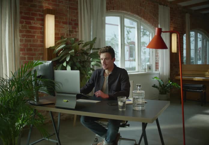 A man is sitting at a desk with a computer having a video conference