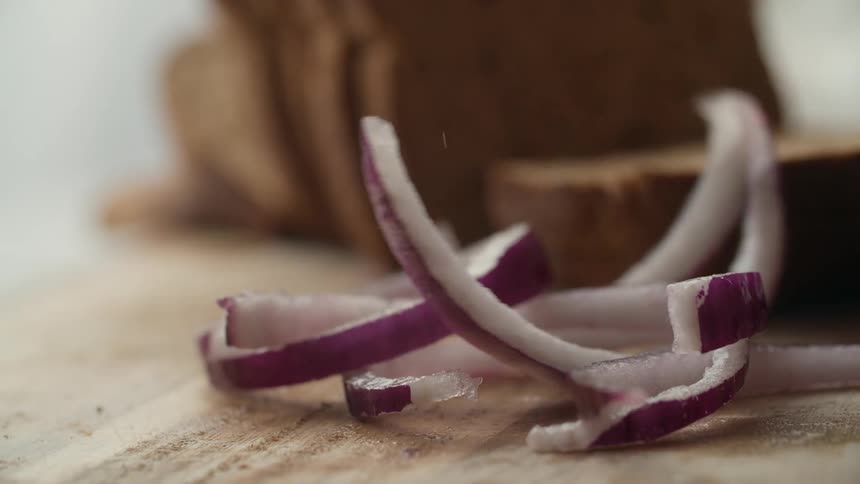 Slices of red onions falling on a cutting board