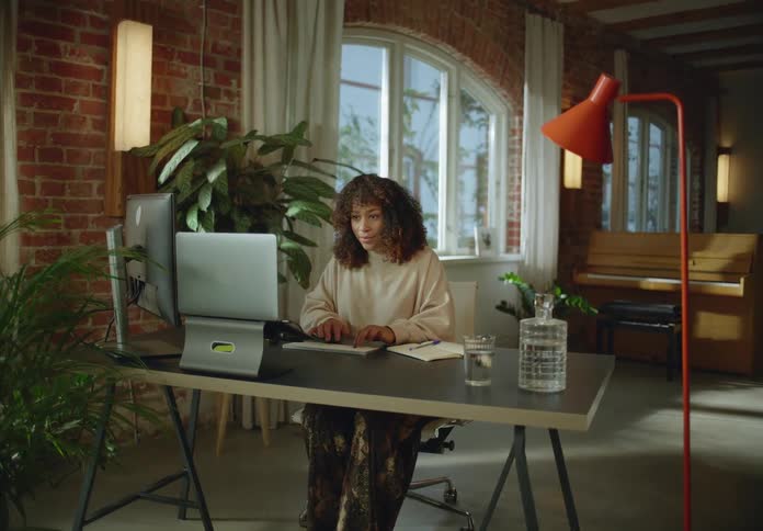 A woman types on a computer while sitting at a desk indoors during the day